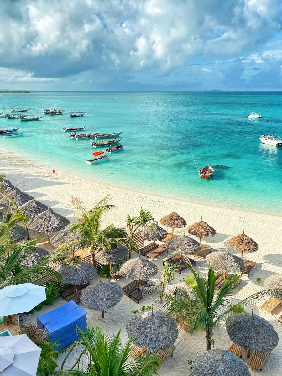 White sand, thatched umbrellas and wooden boats on turquoise water in Zanzibar