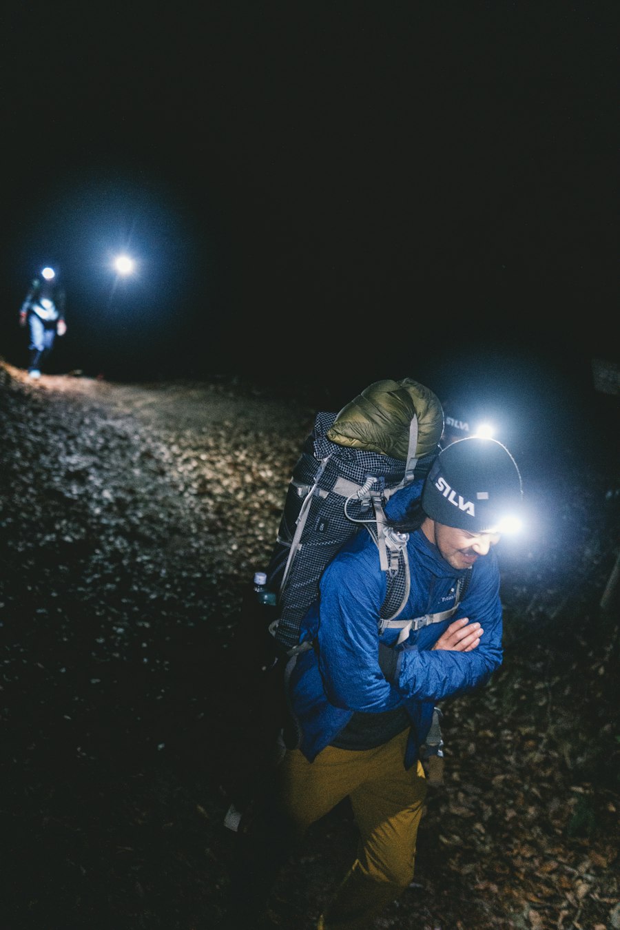 Hiker with a headlamp and a heavy pack on a night trail