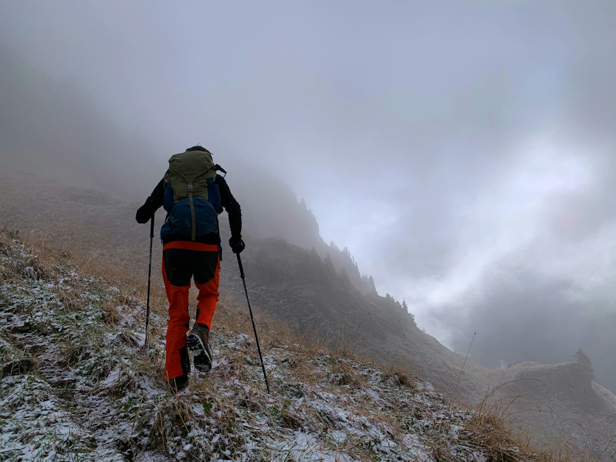 Hiker with trekking poles climbing a misty, frosted slope